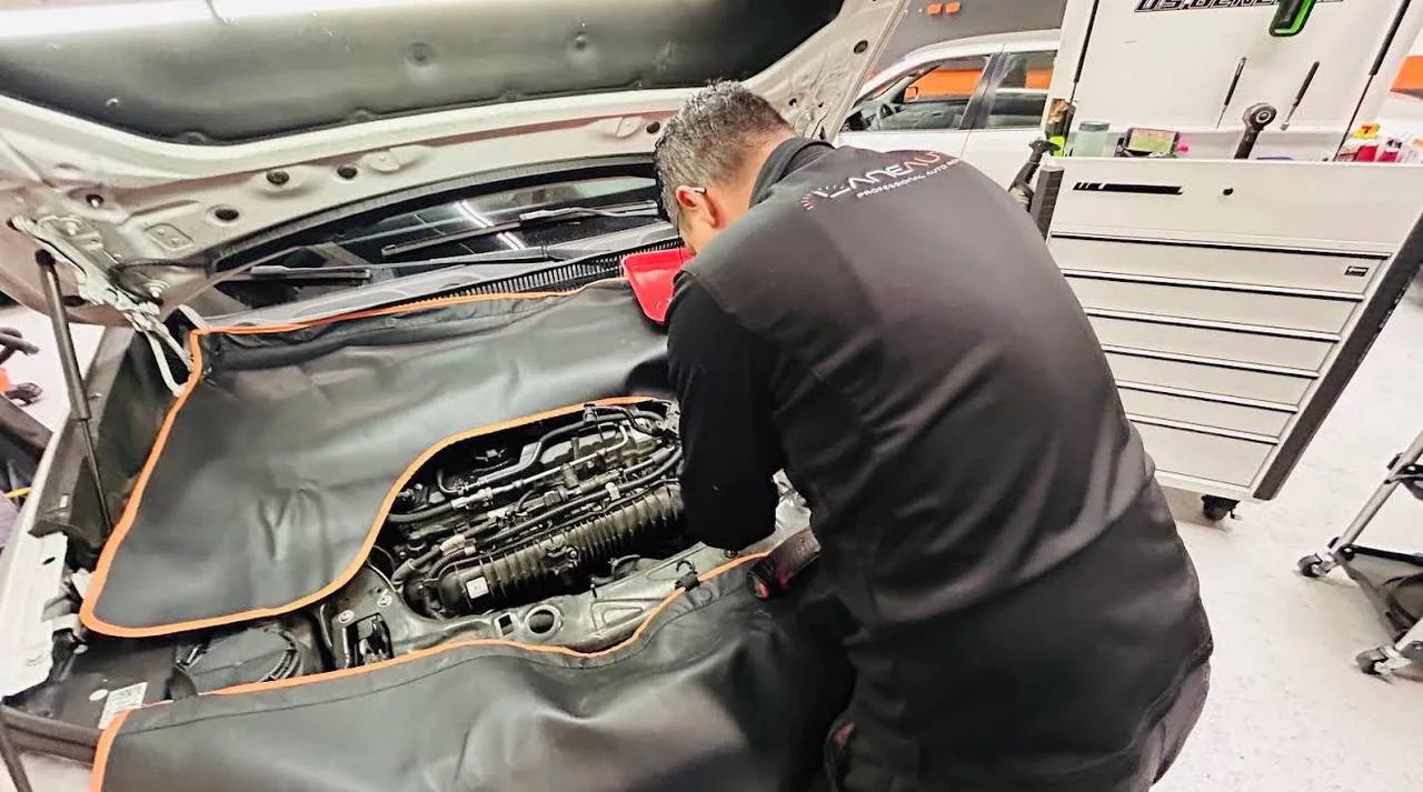 Lane Auto technician performing detailed work under an open hood