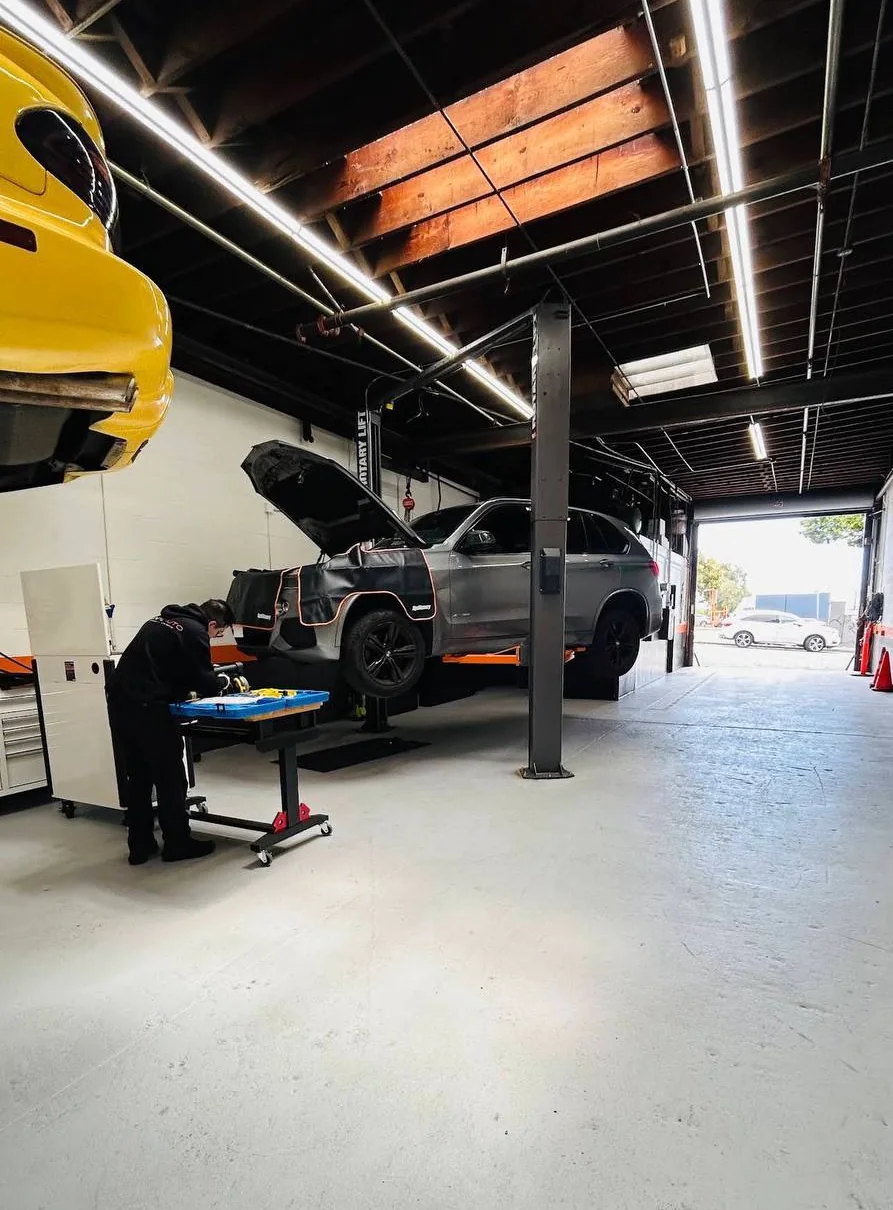 Lane Auto technician working beside a vehicle on a lift
